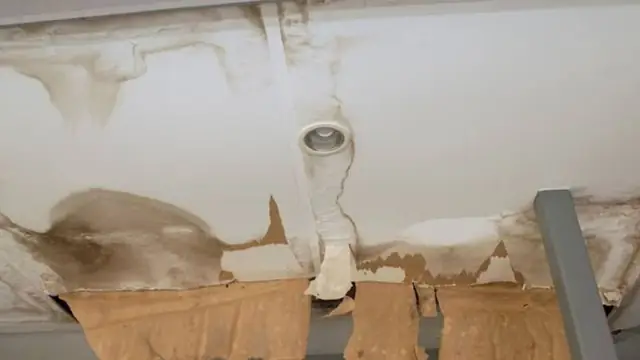 Water-stained ceiling with a recessed light and peeling drywall