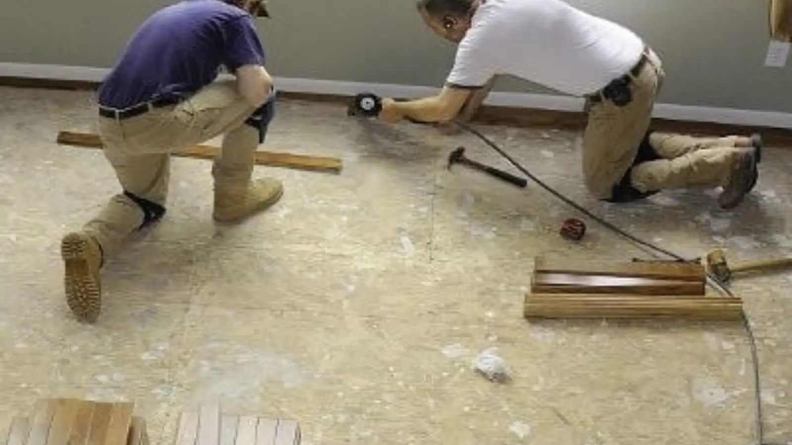 Two contractors working on a floor during a water damage repair